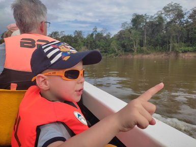 Neugieriges Kind im Boot beim Erkunden des Kinabatangan-Flusses – Malaysia & Borneo Familienreise