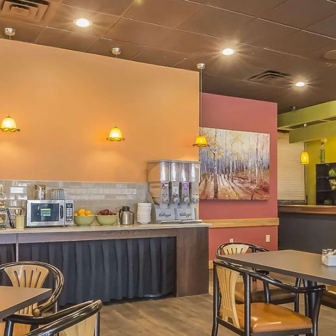 Ein einladendes Restaurant mit warmen Farben, Tischen und Stühlen, ideal für entspannte Mahlzeiten.