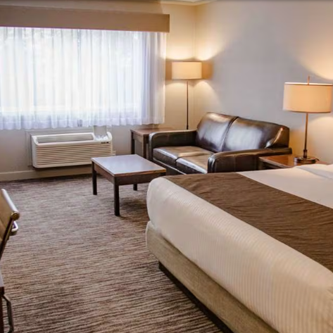 Ein einladendes Hotelzimmer mit einem großen Fenster, einer gemütlichen Couch und einem stilvollen Schreibtisch.