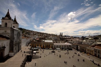 Ein weitläufiger Platz in Quito, umgeben von historischen Gebäuden und Menschen, die die Atmosphäre genießen.