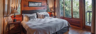 Ein gemütliches Schlafzimmer mit einem großen Bett, dekoriert mit Kissen mit Elefantenmotiven und warmem Holzinterieur.