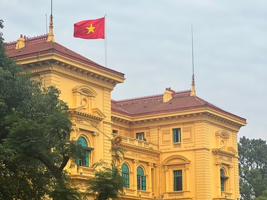 Das prächtige gelbe Gebäude mit dem vietnamesischen Flagge weht über dem Präsidentenpalast in Hanoi, umgeben von üppigem Grün.