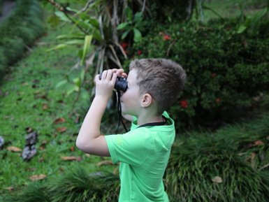 Junge erkundet die Natur mit Fernglas in der Maquenque Eco Lodge – Familienreise Costa Rica