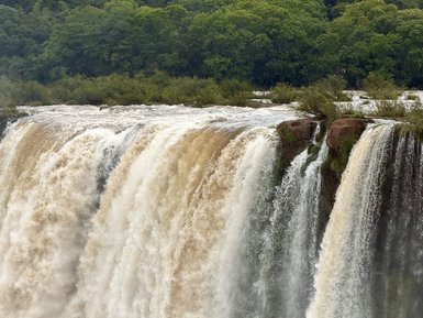 Majestätische Wasserfälle stürzen mit großer Kraft in eine grüne Schlucht, umgeben von üppigem Dschungel.