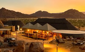 Eine malerische Aussicht auf das Twyfelfontein Adventure Camp, umgeben von majestätischen Bergen und sanften Hügeln.