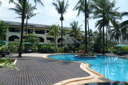 Ein einladender Pool umgeben von Palmen und üppigem Grün, mit einem modernen Hotel im Hintergrund, ideal für Entspannung.
