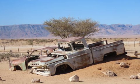Ein rostiges Auto steht verlassen in der Wüste - Namibia mit Kindern