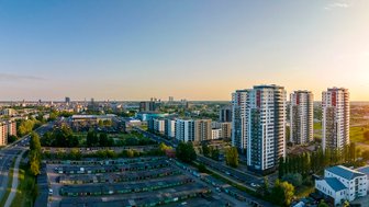 Eine weite Stadtansicht von Riga zeigt moderne Hochhäuser und grüne Flächen unter einem klaren Himmel.