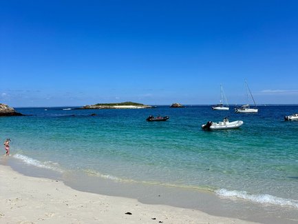 Ein sonniger Strand mit feinem, weißem Sand und klarem, türkisfarbenem Wasser, ideal für einen entspannten Tag am Meer.