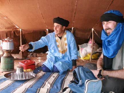 Beduine reicht marokkanischen Minztee in der Wüste – Familienreise nach Marokko