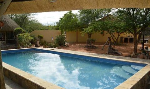 Ein klarer Pool spiegelt den Himmel wider, umgeben von üppigem Grün und einem einladenden Gartenbereich.