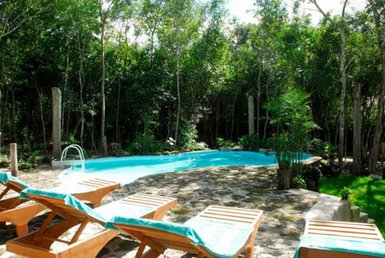 Ein einladender Pool umgeben von üppigem Grün, mit Liegen aus Holz und blauen Handtüchern für entspannende Stunden.
