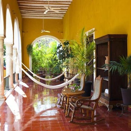 Ein einladender Innenhof mit gelben Wänden, einer Hängematte und Pflanzen, die eine entspannte Atmosphäre schaffen.