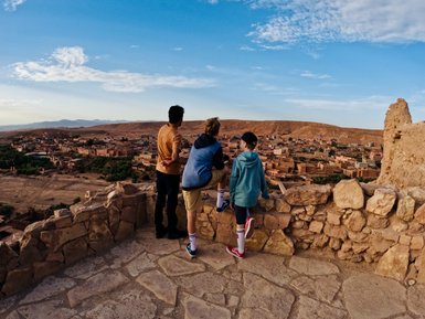 Kinder blicken über eine Mauer auf die Stadt Aït Ben Haddou in Marokko – Familienreise nach Marokko
