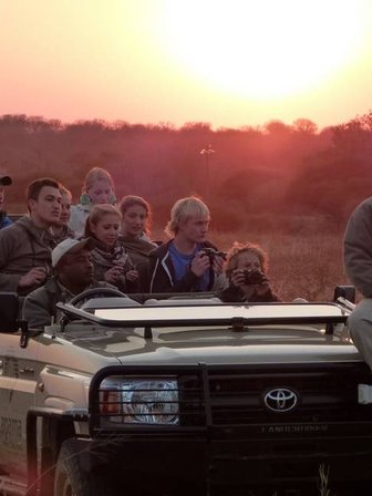 Reisegruppe im offenen Safari-Jeep entdeckt die Tierwelt bei Nacht – Südafrika mit Kindern