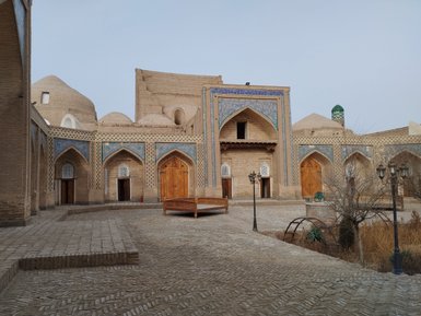Eine historische Architektur mit kunstvollen Fliesen und Holztüren, umgeben von einem gepflasterten Innenhof.