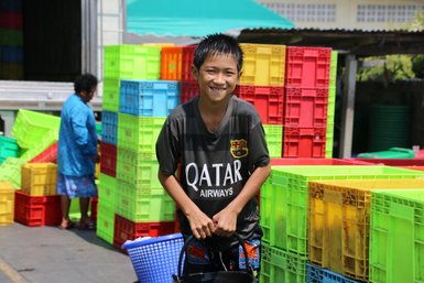 Kind inmitten der farbenfrohen Häuser eines thailändischen Fischerdorfs – Thailand Reise mit Kindern