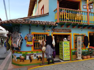 Bunte Fassade eines Geschäfts in Guatapé, mit handgefertigten Kleidungsstücken und einem lebhaften Balkon im Obergeschoss.