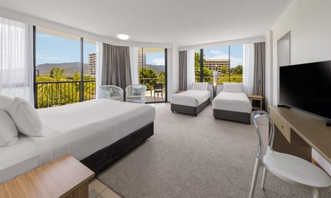 Ein großzügiges Hotelzimmer mit zwei Betten, modernen Möbeln und großen Fenstern, die einen Blick auf die Natur bieten.