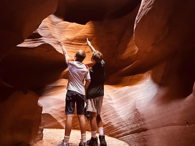 Zwei Kinder stehen in einer engen Schlucht und zeigen begeistert auf die beeindruckenden Felsformationen über ihnen.