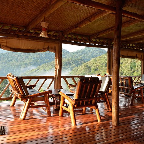 Eine gemütliche Veranda mit Holzstühlen bietet einen atemberaubenden Blick auf die bewaldeten Hügel im Hintergrund.