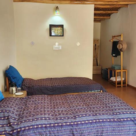 Zwei Einzelbetten mit blauen Kissen in einem gemütlichen Raum, dekoriert mit einem kleinen Bild an der Wand.