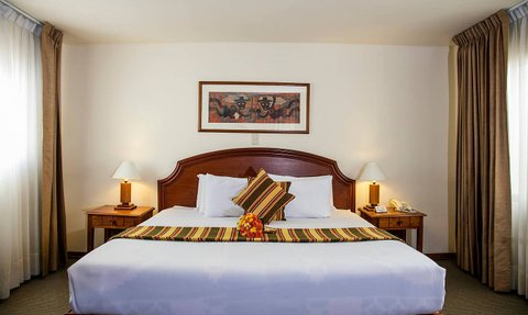 Ein gemütliches Hotelzimmer mit einem großen Bett, dekoriert mit bunten Kissen und einer frischen Blumenarrangement.