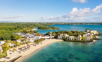 Ein atemberaubender Blick auf das luxuriöse Resort am Strand, umgeben von üppigem Grün und klarem, blauem Wasser.