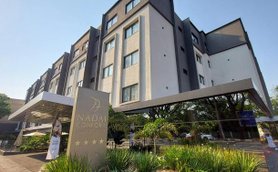 Das moderne Hotel Nadia Confort beeindruckt mit seiner stilvollen Architektur und einladender Pflanzenlandschaft im Vordergrund.