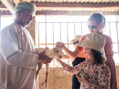 Kinder streicheln Ziege bei einem Farmbesuch im Oman – Oman mit Kindern