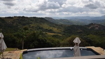 Ein ruhiger Pool mit Blick auf sanfte Hügel und bewaldete Landschaften unter einem bewölkten Himmel.