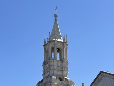Der hohe Turm einer beeindruckenden Kirche erhebt sich majestätisch gegen den klaren blauen Himmel.