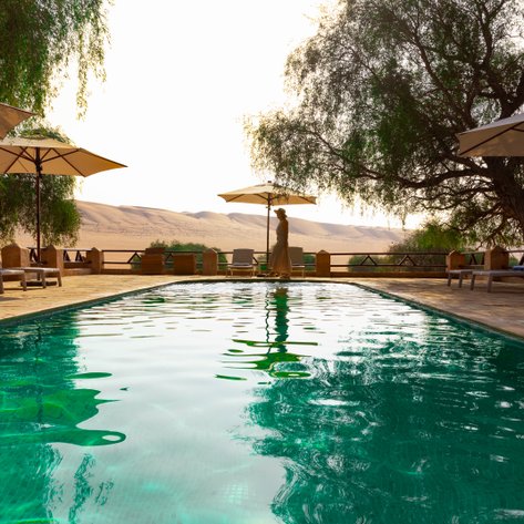 Erfrischender Pool im Thousand Nights Camp mit Blick auf die goldenen Sanddünen – Oman mit Kindern