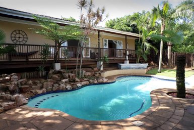 Ein einladender Pool umgeben von üppigem Grün und einem Holzdeck, ideal für entspannende Tage im Freien.