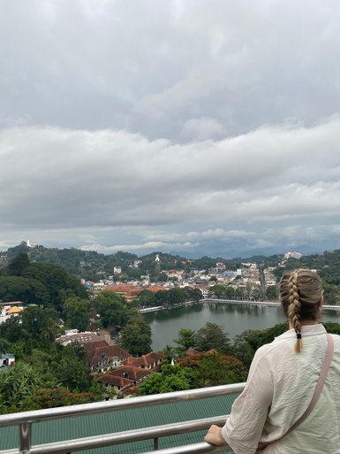 Teenagerin steht auf einem Aussichtspunkt und blickt über die Stadt Kandy – Sri Lanka Reise mit Kindern