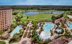 Ein luxuriöses Resort mit mehreren Pools, umgeben von üppigen Gärten und einem Golfplatz im Hintergrund.