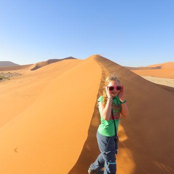 Ein Kind läuft eine Düne hinauf - Namibia Urlaub mit Kindern