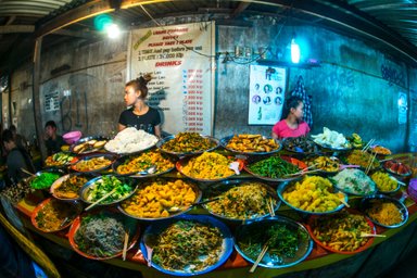 Ein lebhafter Nachtmarkt in Luang Prabang mit einer Vielzahl von bunten, frisch zubereiteten Speisen auf einem Tisch.