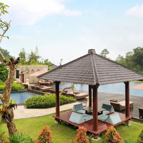 Ein stilvoller Pavillon mit bequemen Sitzgelegenheiten steht in einem üppigen Garten neben einem glitzernden Pool.