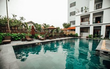 Ein ruhiger Hotelpool umgeben von üppigem Grün und gemütlichen Liegen, ideal zum Entspannen und Erholen.