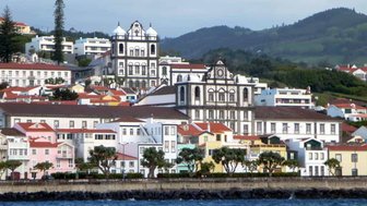 Blick auf die farbenfrohen Gebäude von Faial, umgeben von üppigem Grün und dem ruhigen Wasser des Ozeans.