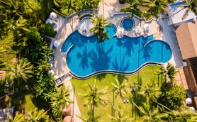 Ein luftiger Blick auf einen großen Pool, umgeben von Palmen und Liegen, ideal für Entspannung und Erholung.