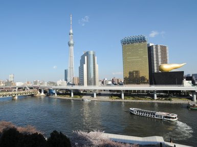Der Sumida-Fluss fließt ruhig durch Tokio, umgeben von modernen Wolkenkratzern und der ikonischen Tokyo Skytree.