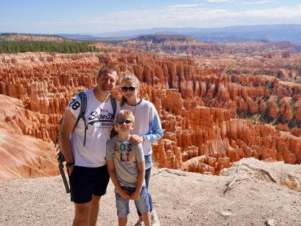 Eine Familie steht am Rand des Bryce Canyon, umgeben von beeindruckenden roten Felsformationen und einer weiten Landschaft.