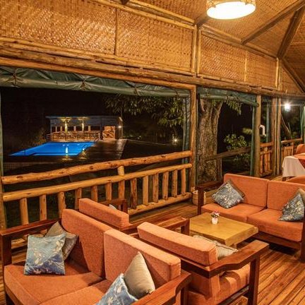 Eine gemütliche Lounge mit bequemen Sofas und einem Blick auf einen beleuchteten Pool im Hintergrund.