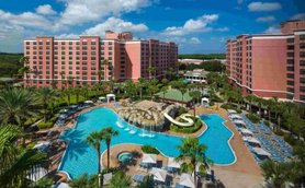 Ein Blick auf den großzügigen Poolbereich des Caribe Royal Resorts, umgeben von Palmen und Sonnenliegen unter klarem Himmel.
