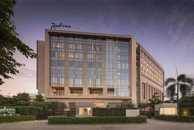 Das moderne Radisson Hotel in Delhi zeigt eine elegante Fassade mit großen Fenstern und einem einladenden Eingangsbereich.