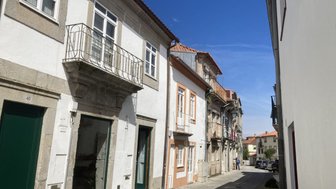 Eine enge Gasse mit historischen Gebäuden, die von strahlend blauem Himmel und Sonnenschein beleuchtet wird.