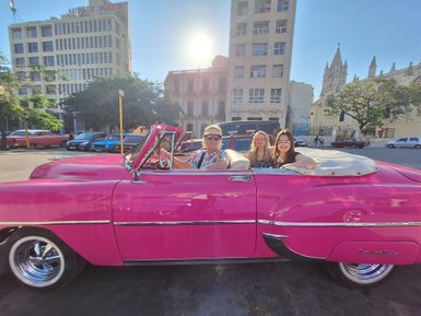Drei Frauen sitzen in einem pinken Oldtimer-Cabrio in Havanna - Kuba mit Kindern