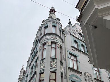 Ein historisches Gebäude in Tallinn mit kunstvollen Verzierungen und großen Fenstern, das in sanften Farben gestrichen ist.